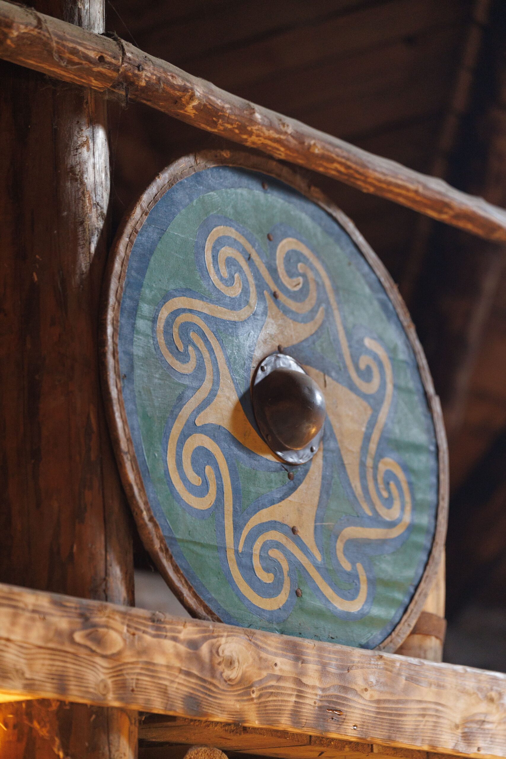 Colorful Viking shield with Celtic pattern displayed in a wooden structure.